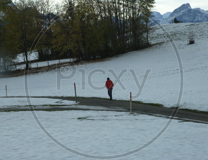 A Man Walking Through a Pathway With Snow On Both sides Of it
