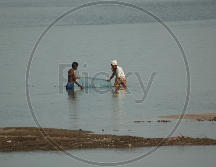 Fisher man Catching Fish with Nets on River banks