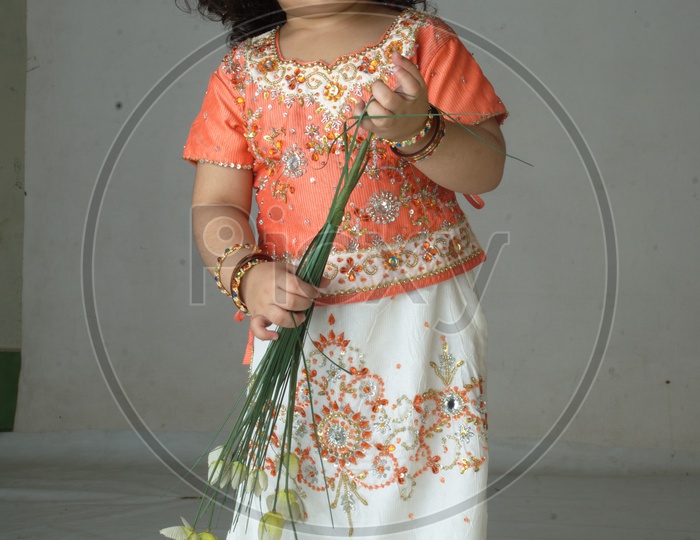 Indian Girl kid in a studio playing with plastic flowers