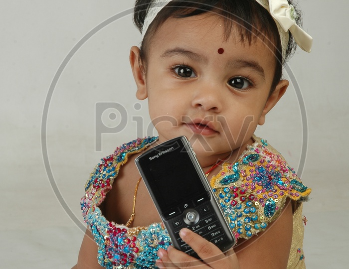 Adorable Indian Girl Child Closeup Shots Holding Mobile Phone  over an Isolated white Background