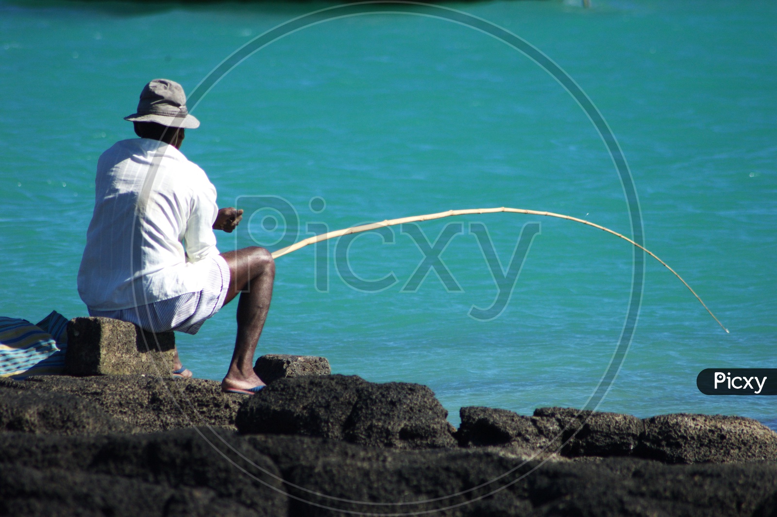 A Man fishing on  a rock beach