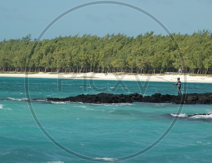 A Fisher Man Fishing With Fishing Road on a Beach