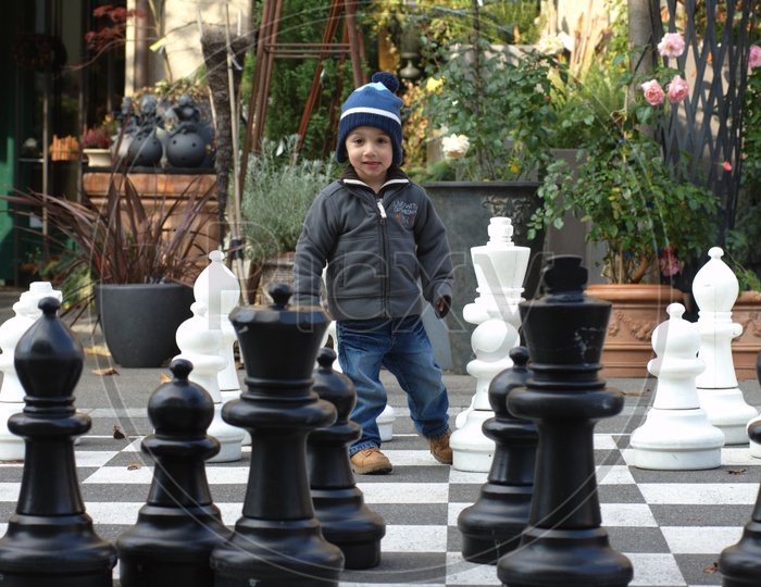 A Boy Child at a Chess Board Drawn on Road and Playing in it