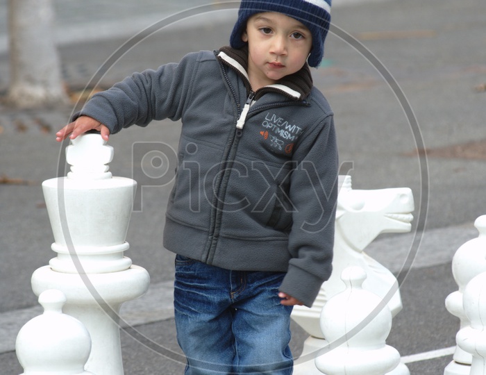 A Boy Child at a Chess Board Drawn on Road and Playing in it