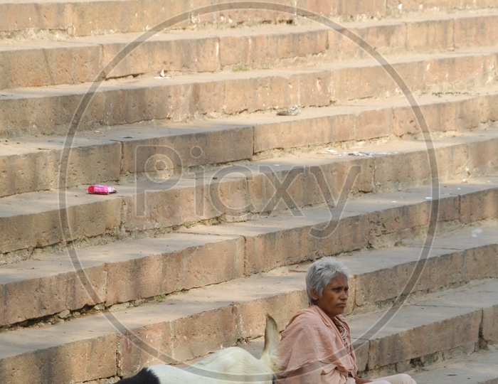 Photograph of a old women  sitting  on steps in a temple / People Face