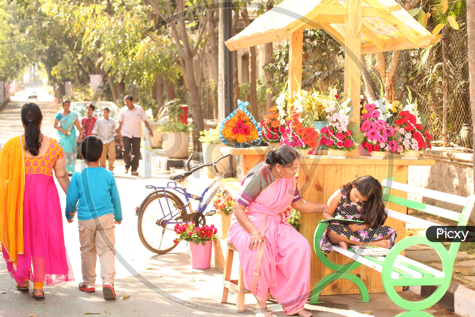 A girl Child reading on a Road Side Flower Vendor Shop in India