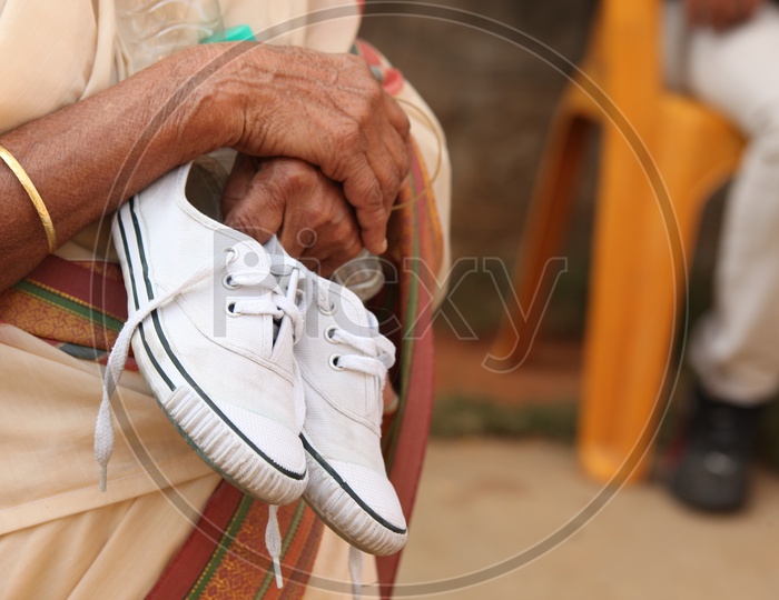 An Old woman Holding Her Grand Daughter Shoe In Hands