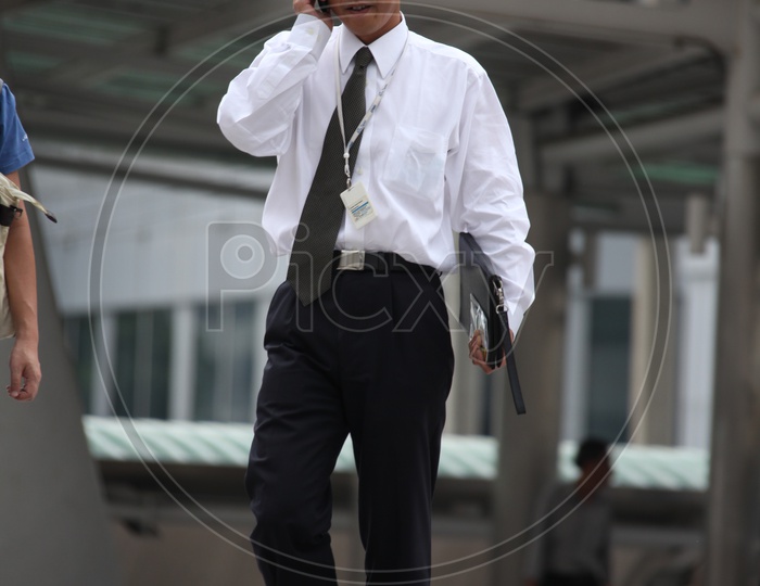 A professional man walking on the road while talking over a phone