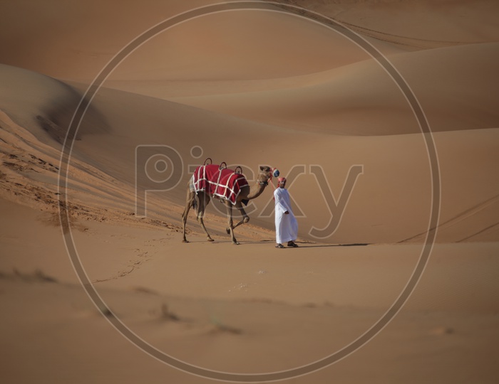 Man  walking with Camel in Dubai Desert