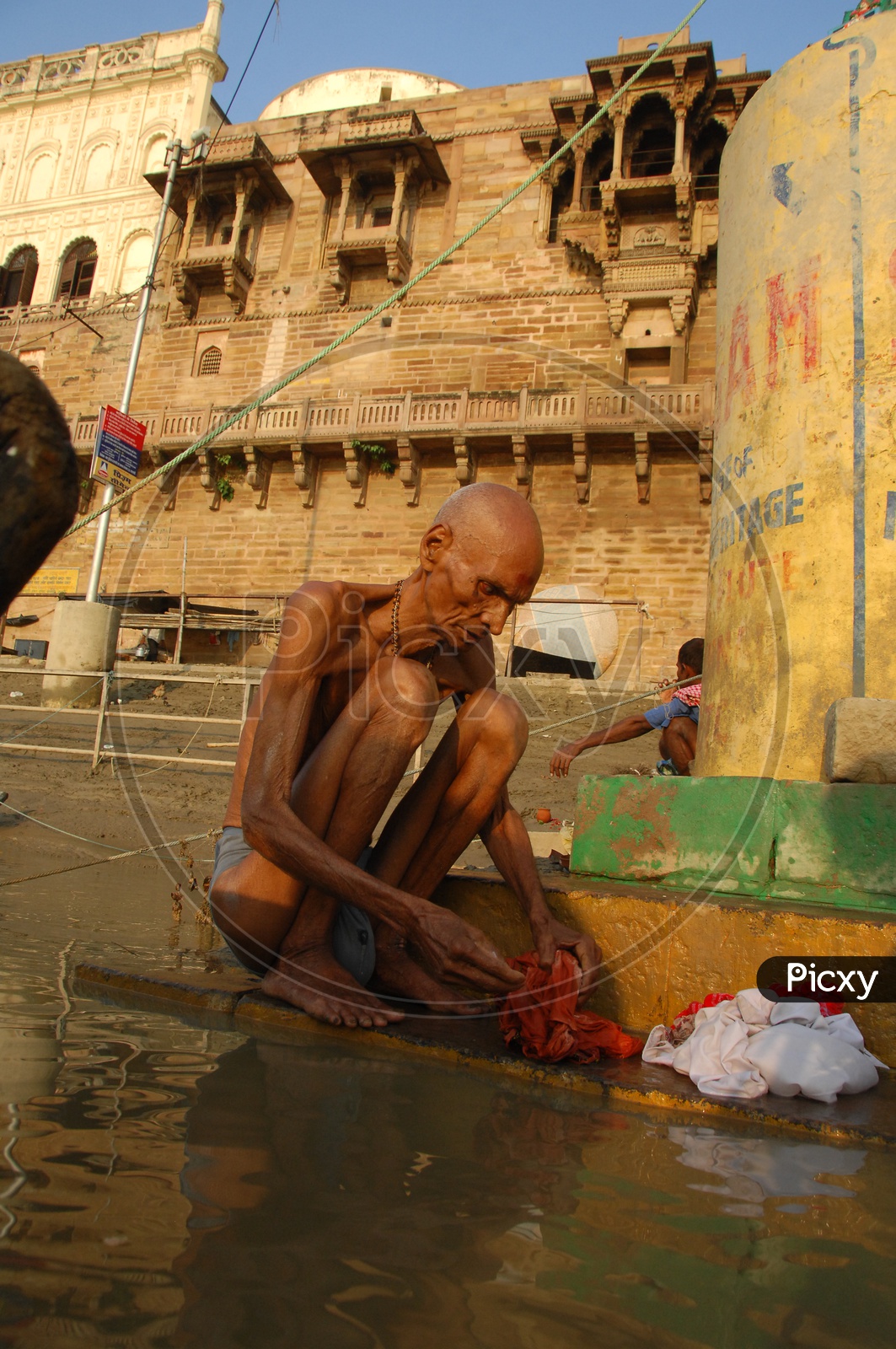 Old man washing clothes in River Ganga in Varanasi
