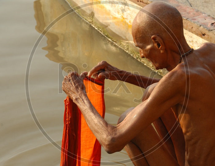 Old man washing clothes in River Ganga in Varanasi
