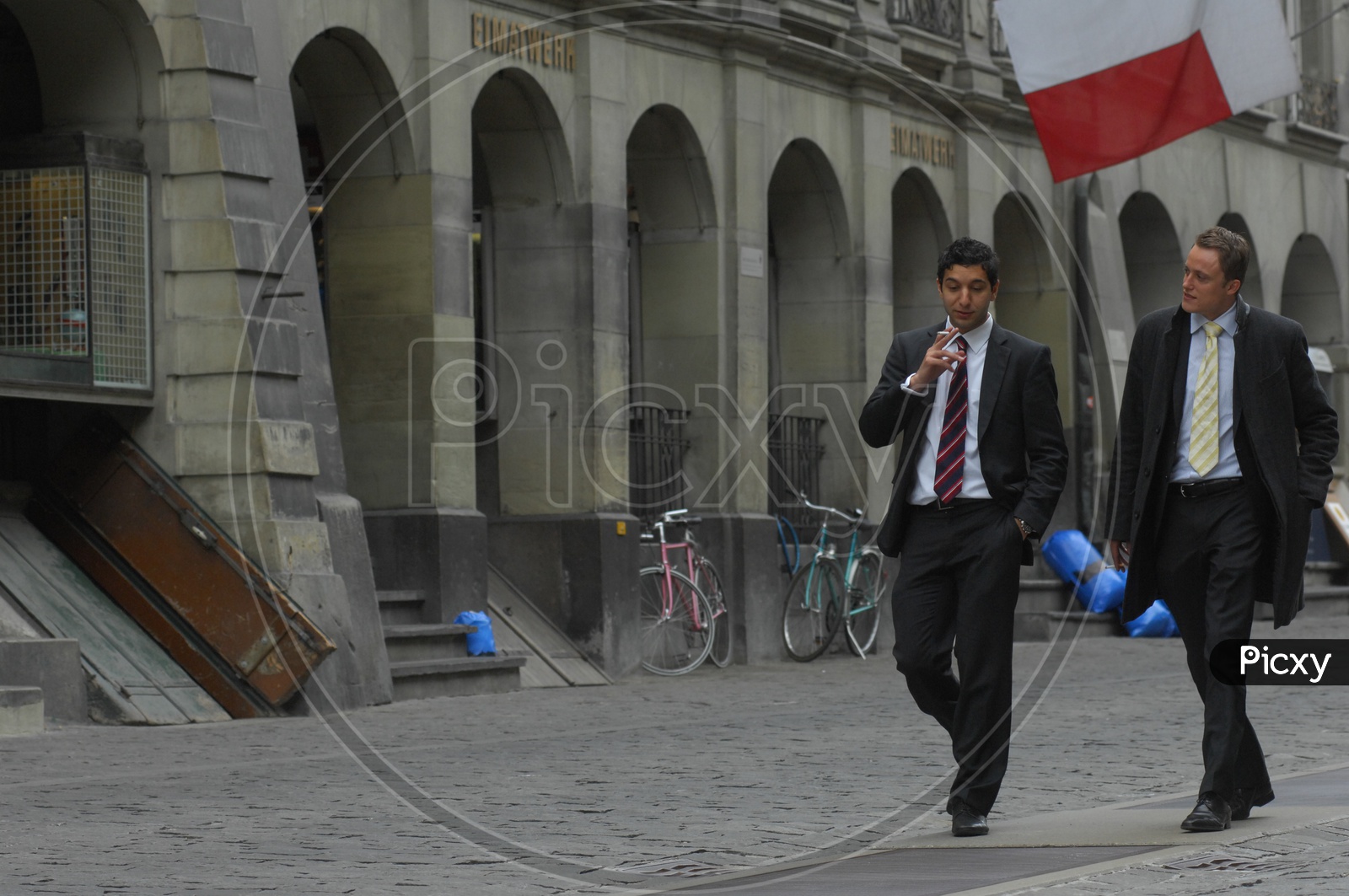 Image of Man In a Suite Walking Along a Street and Smoking a Cigarette -MD781948-Picxy