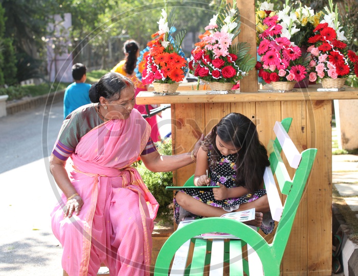 A girl Child reading on a Road Side Flower Vendor Shop in India