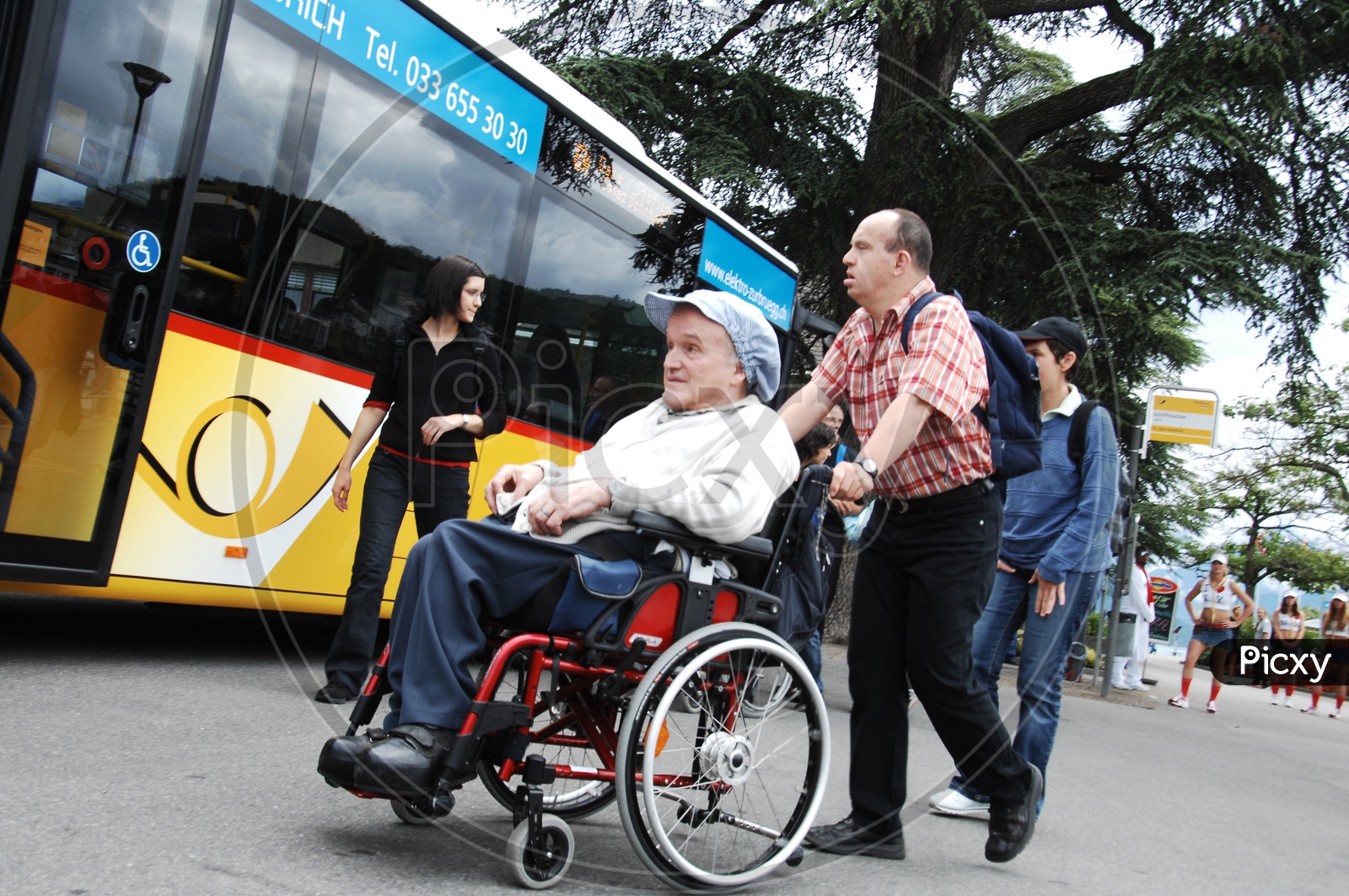 A physically challenged person in a wheelchair pushed by an old man