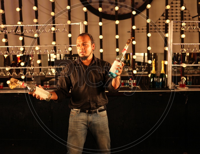 A Bartender Playing With The Fire Lighted Bottles in a Bar