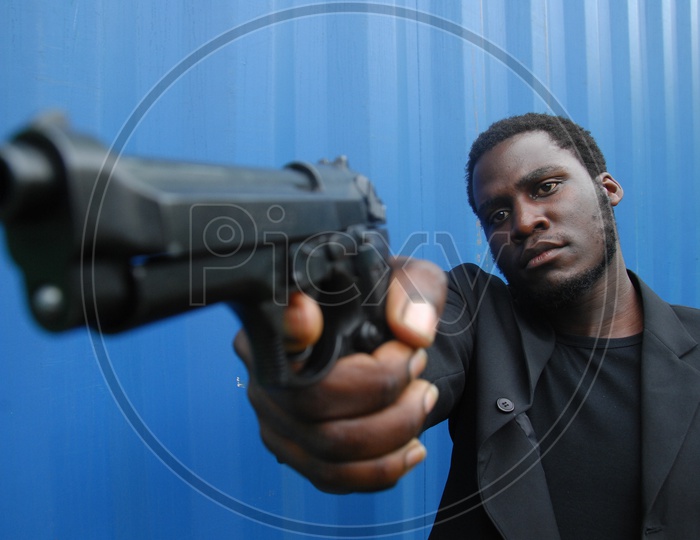 African origin actor holding a gun.  Behind the scenes or the making of film/ Movie Shooting stills