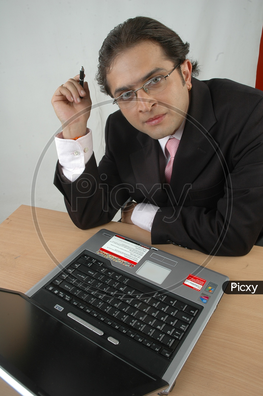 Indian man working and thinking infront of a laptop