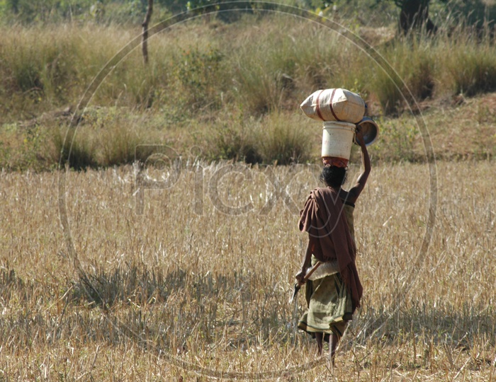 A Woman Carrying Weights On Head in a tribal Village