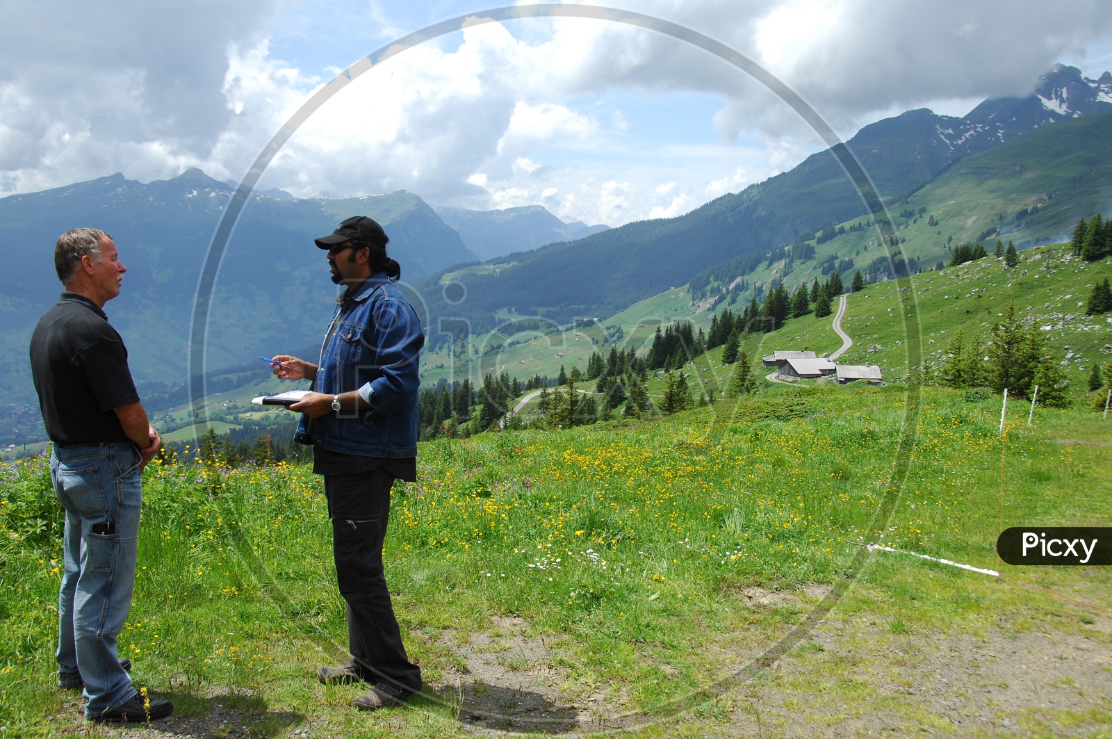 Image of Two men talking near a mountain area, clouds seen at a far ...