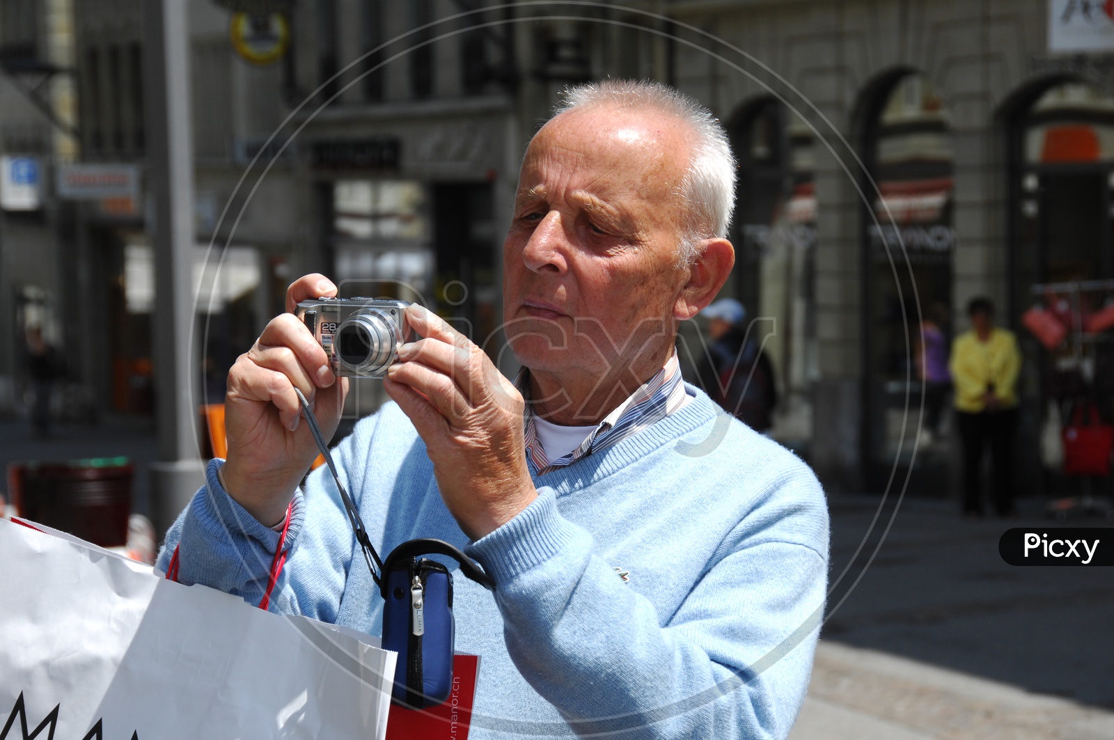 An old man clicking pictures with a camera on the street