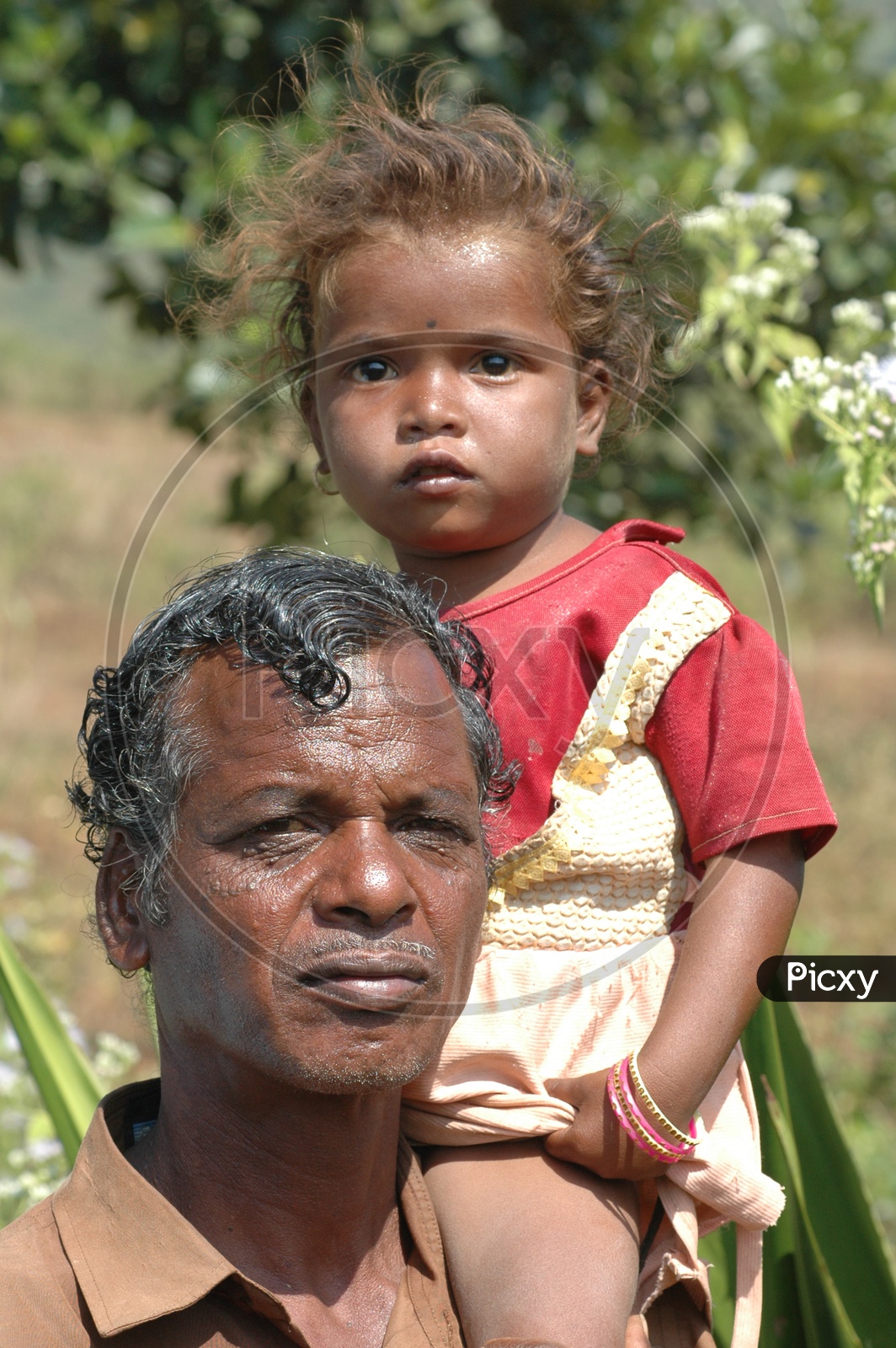 A Tribal Man Carrying His Child On Shoulder