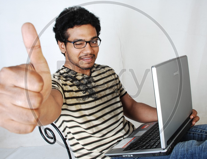 Young Indian Student With Laptop and Thumbsup Gesture