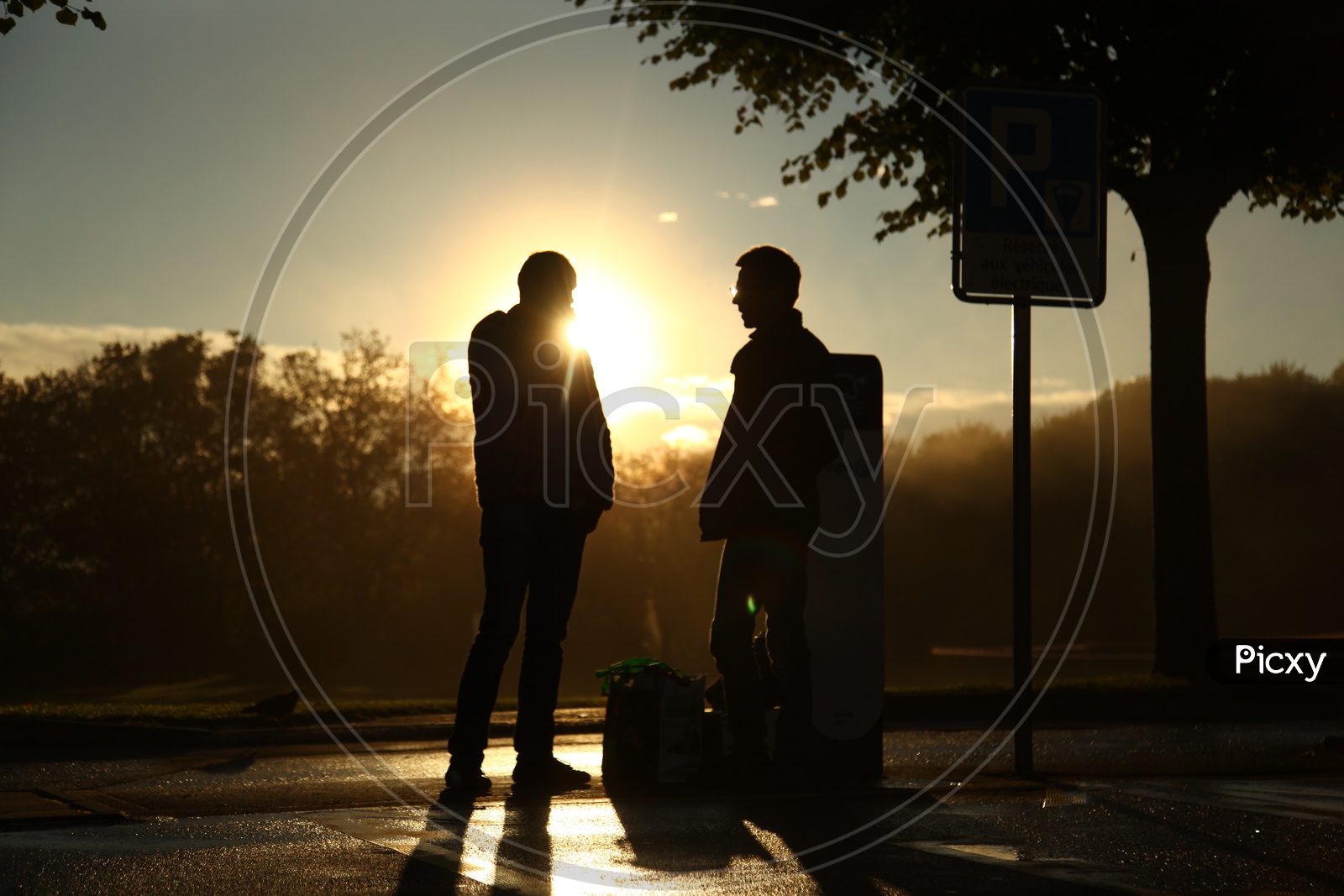 Two men standing viewing the sunset in Silhouette
