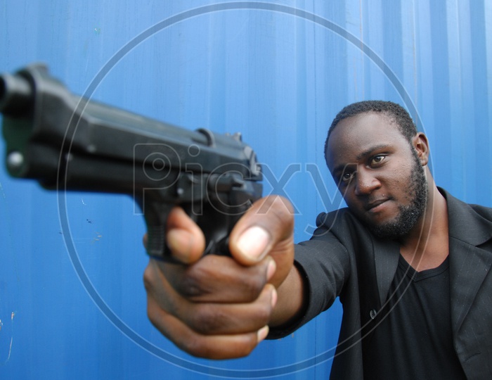 African origin actor holding a gun. Behind the scenes or the making of film/ Movie Shooting stills