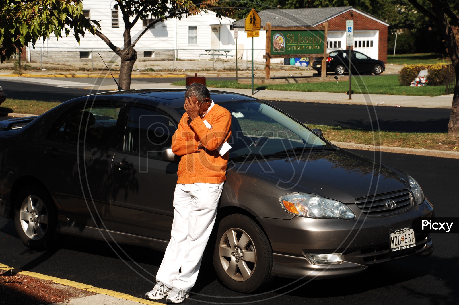 A man standing leaning on a black car