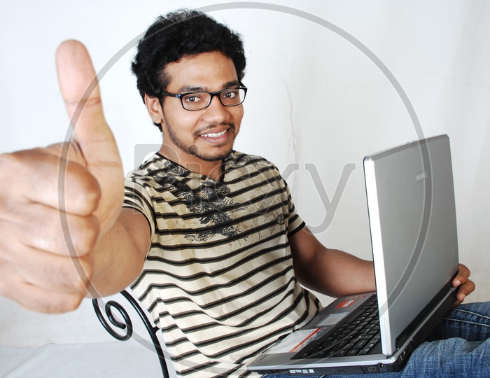 Young indian Student with a laptop Thumpsup gesture