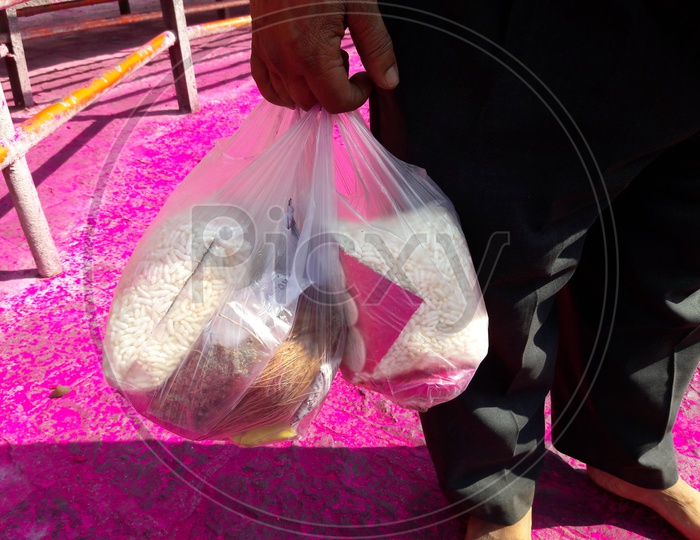 Indian Hindu Devotee Carrying Puffed Rice and Coconut In a Plastic Cover at Hindu Temple