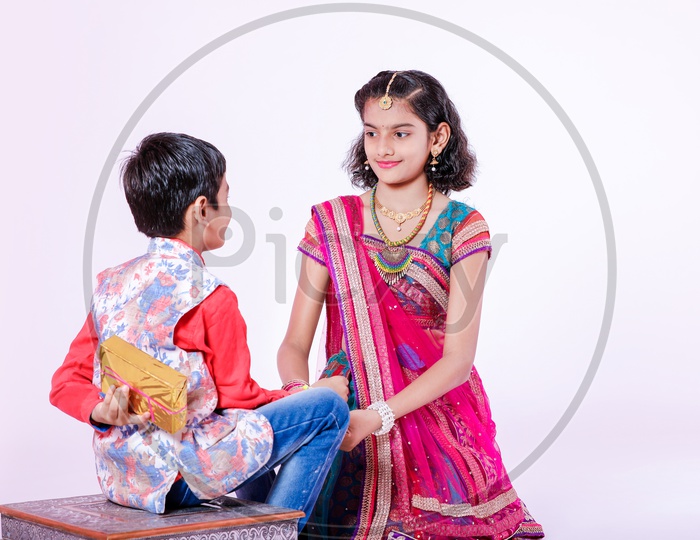 Photograph of cute little brother and sister celebrating Rakhi Festival with white background