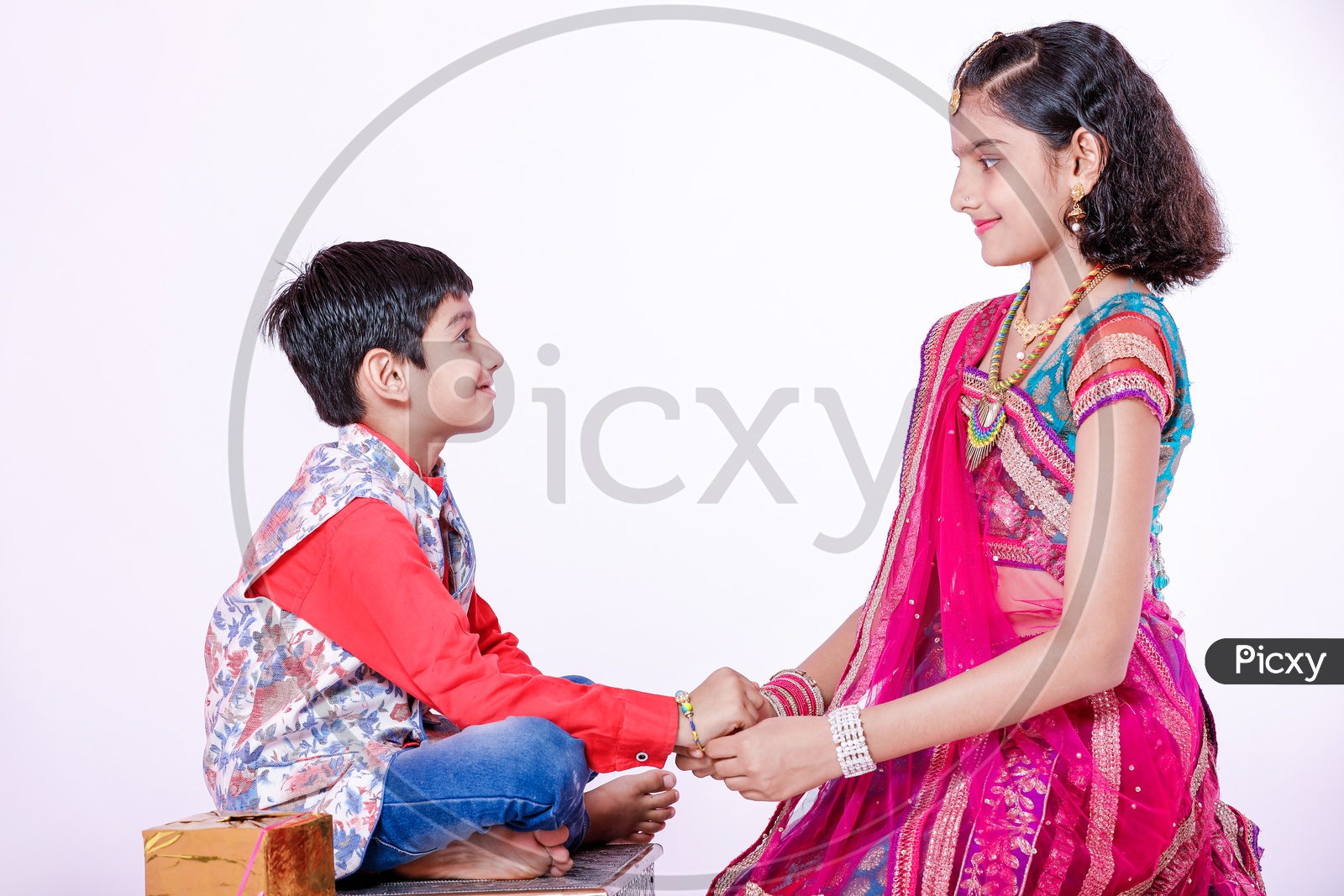 Photograph of cute little brother and sister celebrating Rakhi Festival with white background