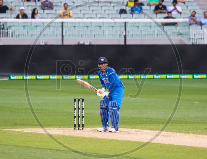 MS Dhoni on a Cricket Stadium  in Batting Position