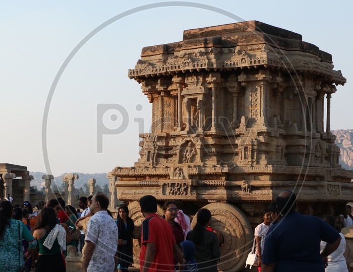 Tourists / Visitors At an  Old Ancient Dravidian Vitthala Temple /  Stone Chariot in Hampi , Karnataka