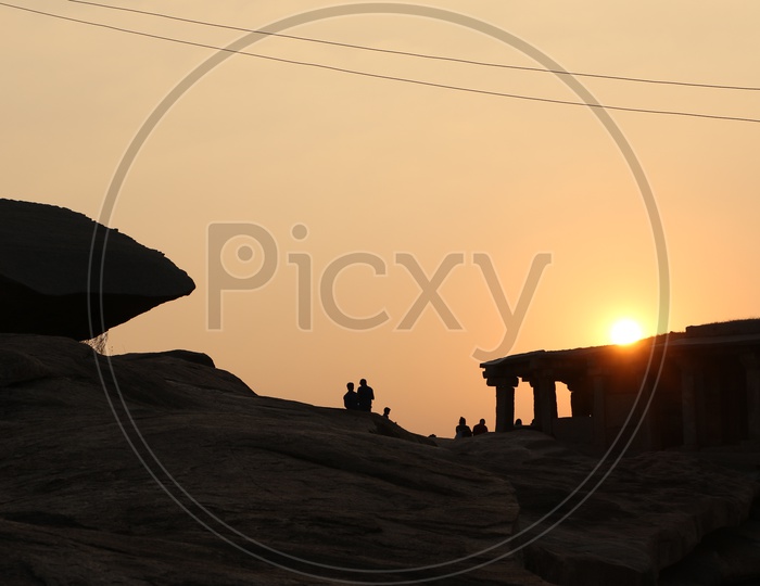 Silhouette  of the Visitors / Tourists Watching the Sunset at  a hill top of Hampi , Karnataka