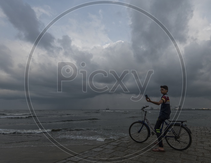 An Indian Young Boy Taking a Selfie On a sea  Shore by Sitting on a Bicycle in Kerala