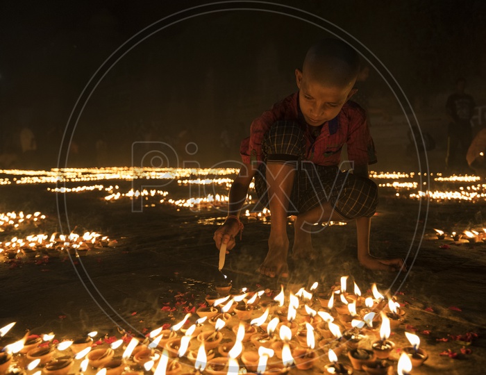 Kid lightening up Diya's in Varanasi