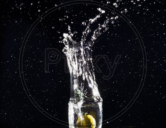 Glass of splashing Water with Lemon with black background