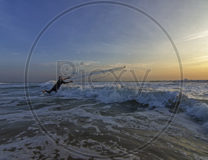 Fisherman spreading the net at dawn in the beach