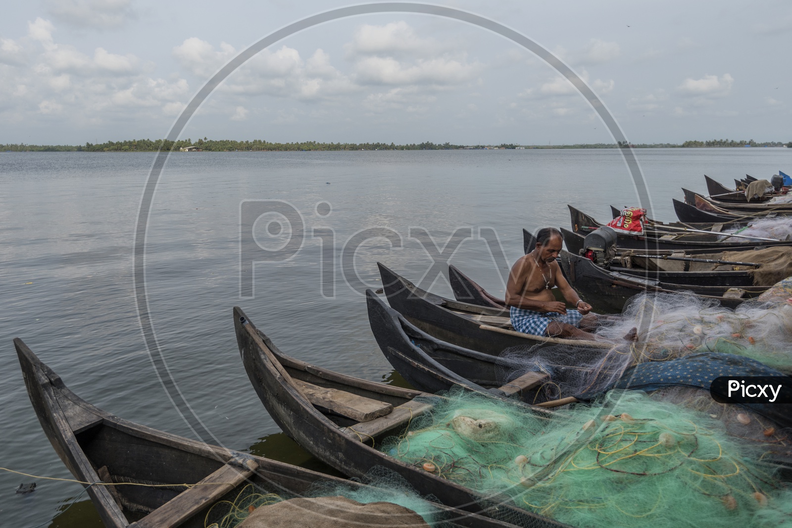 A kerala Fisherman Repairing His Fishing net sitting on boats