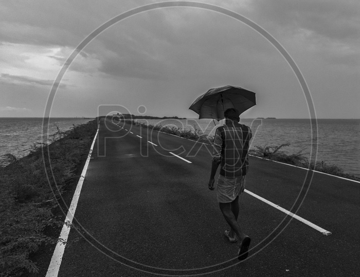 An indian man Holding Umbrella and Walking in rameshwaram