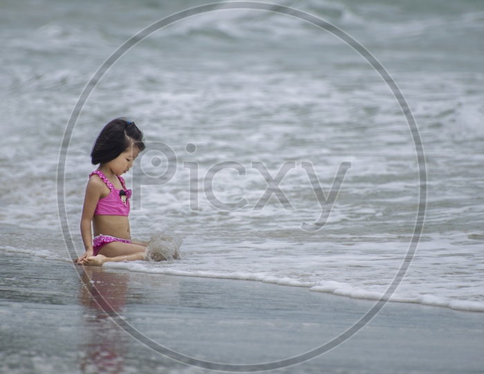 Little girl playing near the beach wave