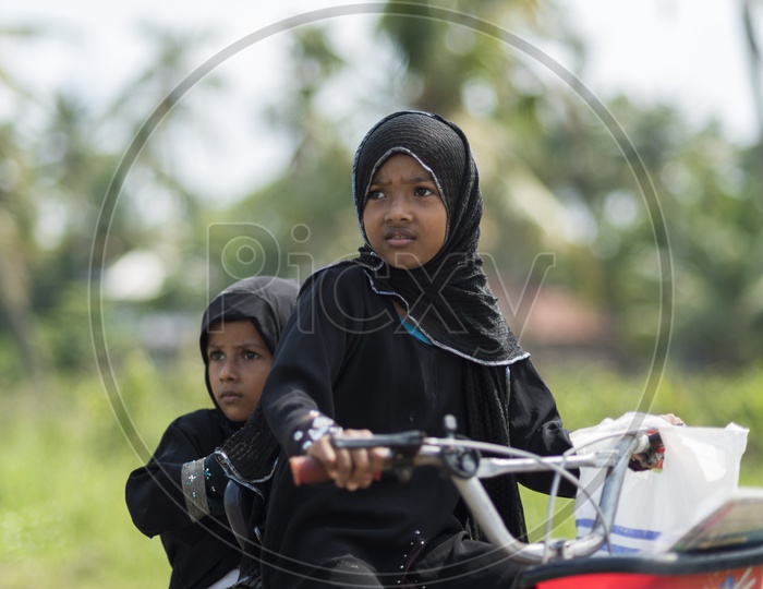 Indian Muslim Girl Child in Burkha Riding Bicycle With Her Sister on  Backside
