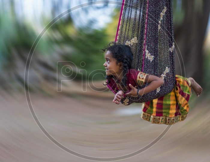 A Panning Shot Of a Girl Child In  a Swing
