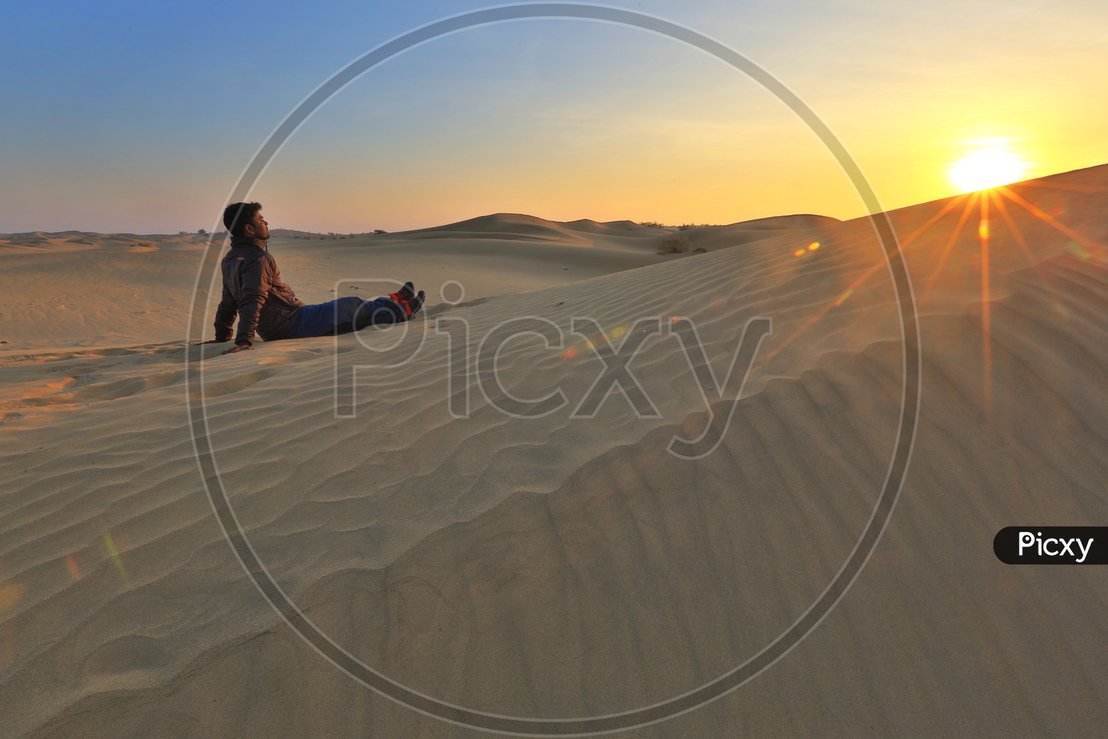 An Indian Man Enjoying The Sunset In a Dessert in Rajasthan Sitting Over Sand Dunes