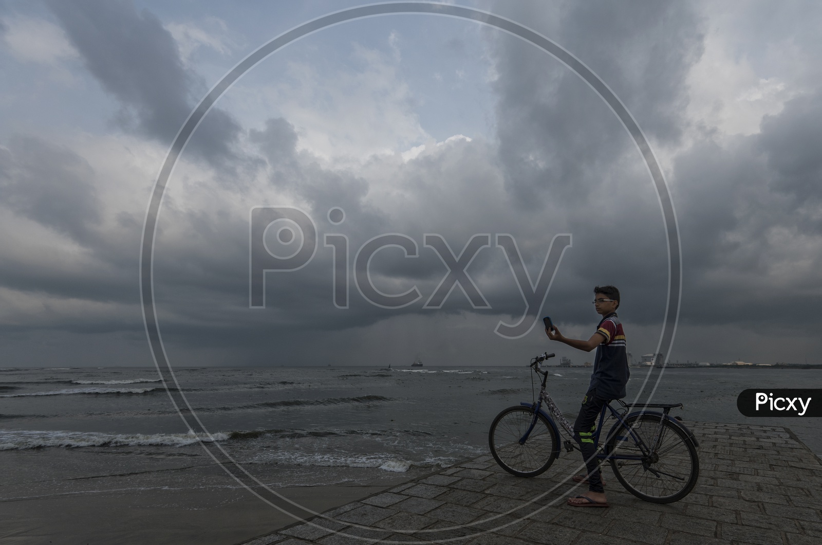An Indian Young Boy Taking a Selfie On a sea  Shore by Sitting on a Bicycle in Kerala