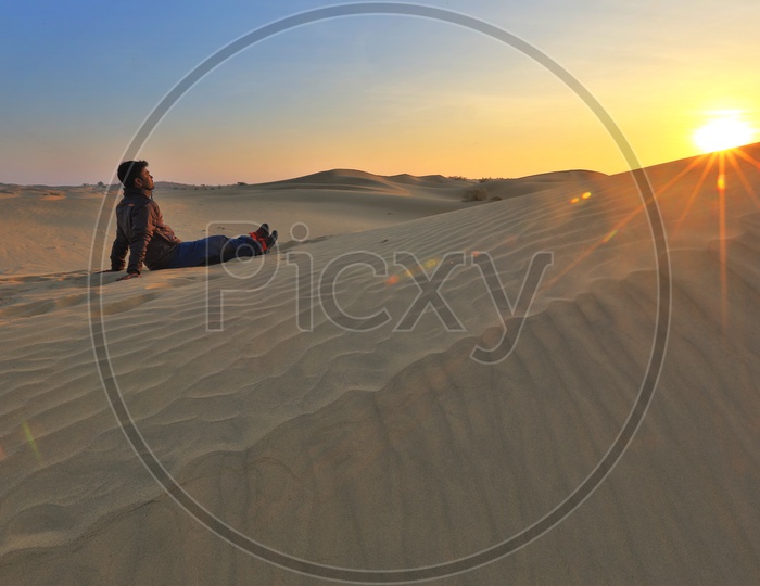 An Indian Man Enjoying The Sunset In a Dessert in Rajasthan Sitting Over Sand Dunes