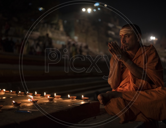 A priest praying after lighting dia's on the eve of Dev Diwali.