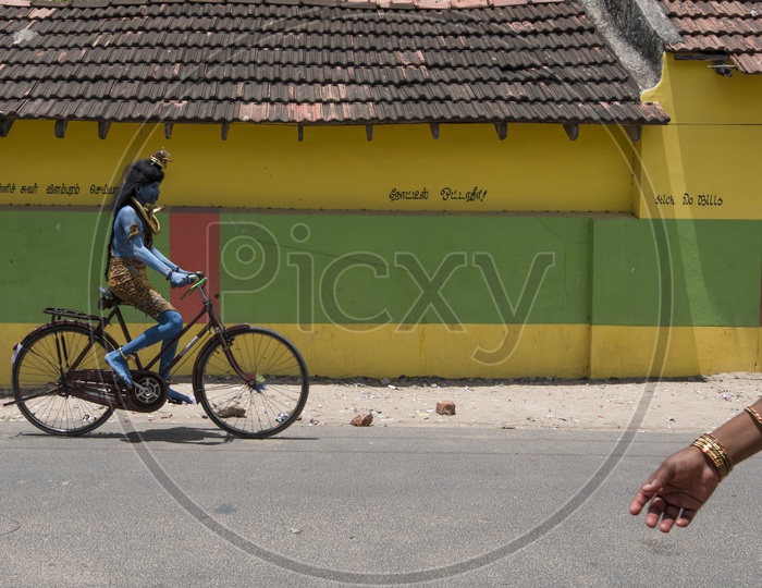 An Indian Boy In Lord Shiva Getup Riding a Bicycle